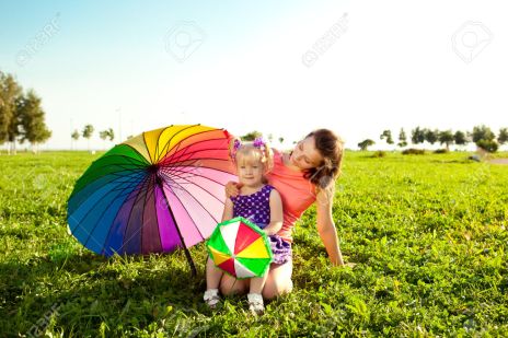 Cute little girl with mother colored balloons and rainbow umbrel